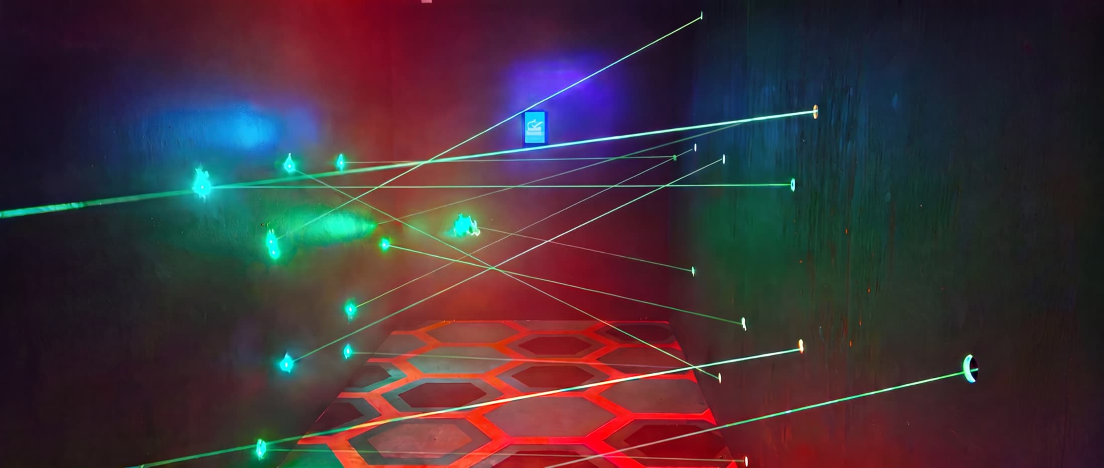 Real ATB Laser Maze installation — green laser beams crossing a dark room with a red hexagonal floor